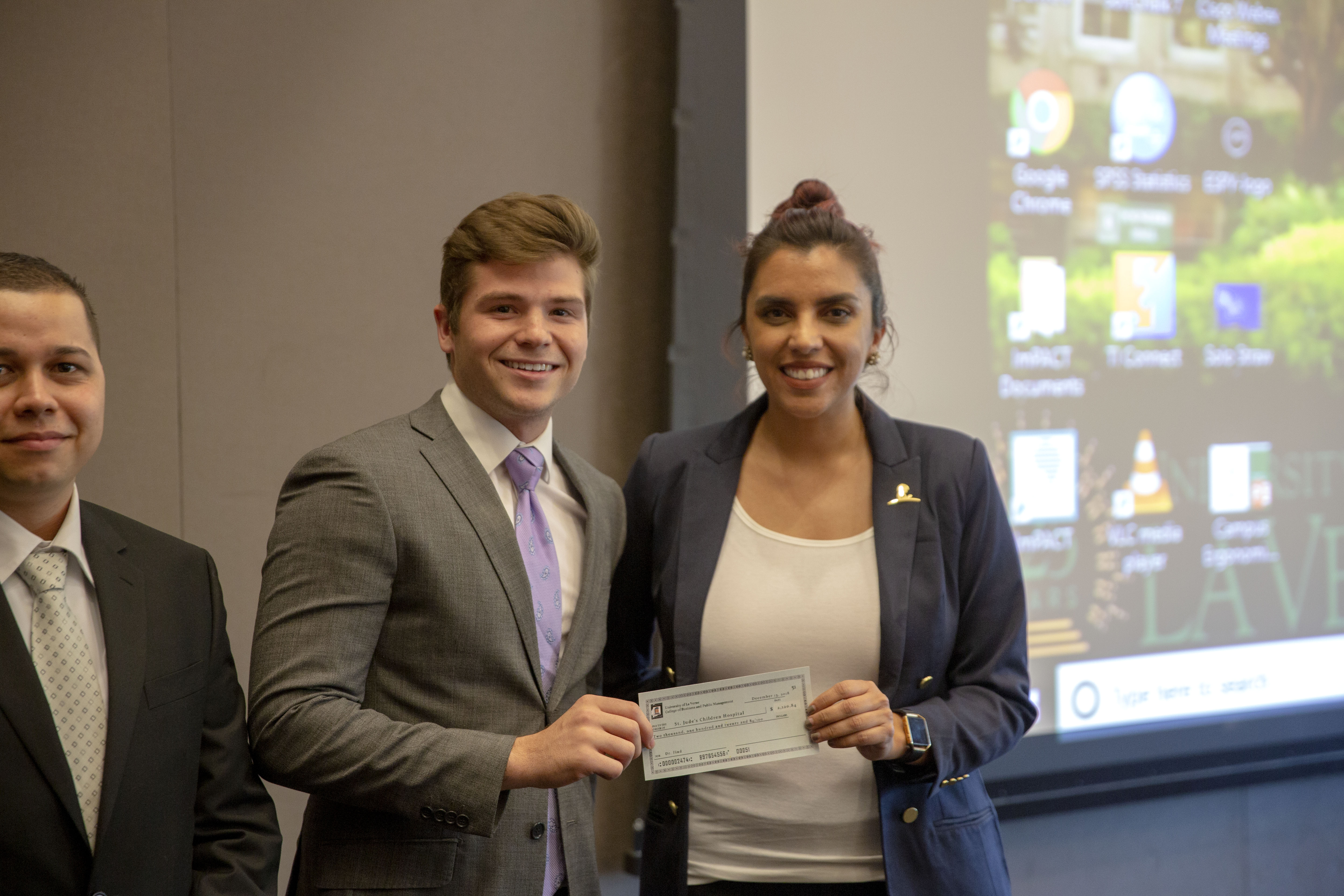 Male student presents check to charity representative