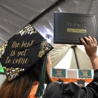 A student shows off her decorated cap and diploma.