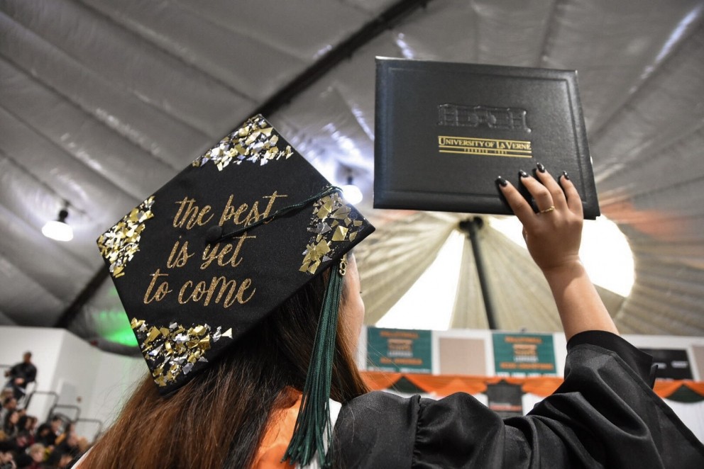 A student shows off her decorated cap and diploma.