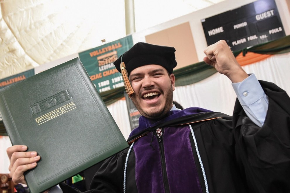A male student celebrates with his degree.