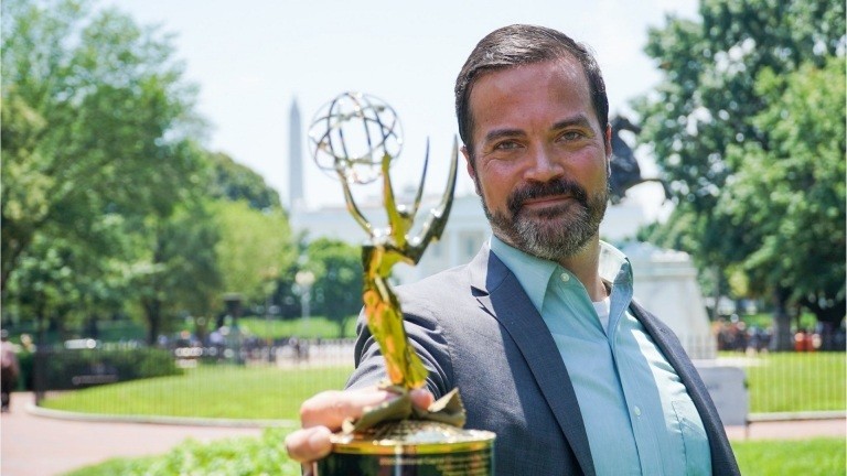Alumnus Nathan Baca holding up Emmy Award