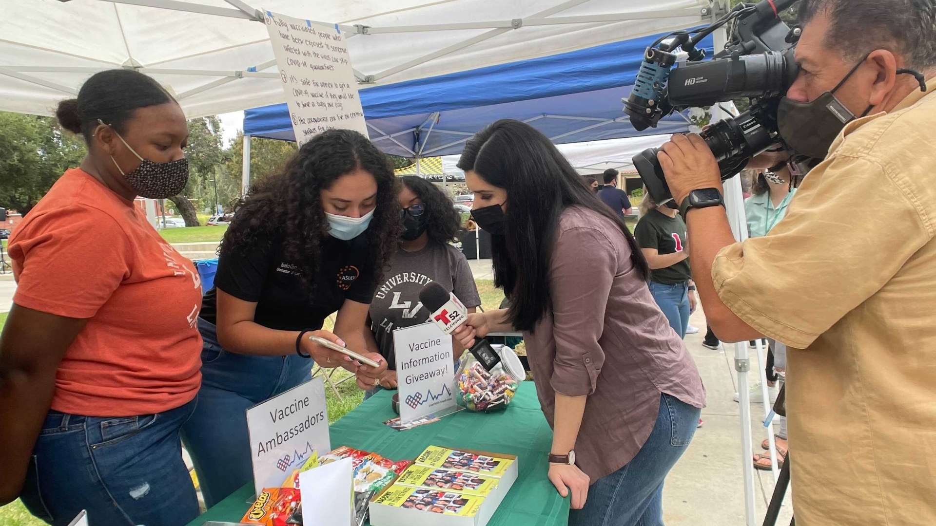 Vaccine Ambassadors Booth with reporter and cameraman