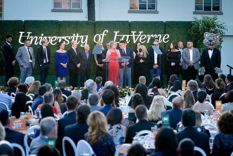 University of La Verne President Devorah Lieberman and student Ian Mendoza on stage at the 2022 Scholarship Gala, along with Mendoza's parents and many of the faculty and staff who helped him on his college journey.