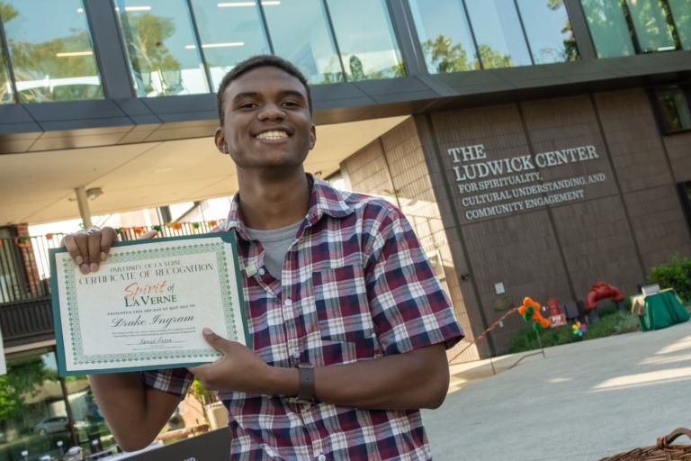 Student Drake Ingram poses with his spirit of la verne certificate.