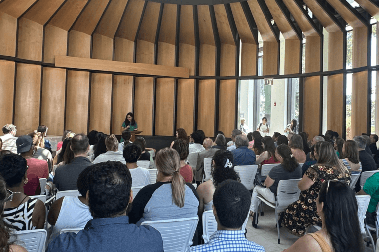 President Mahdavi speaking at a podium to a crowd in the Sacred Space