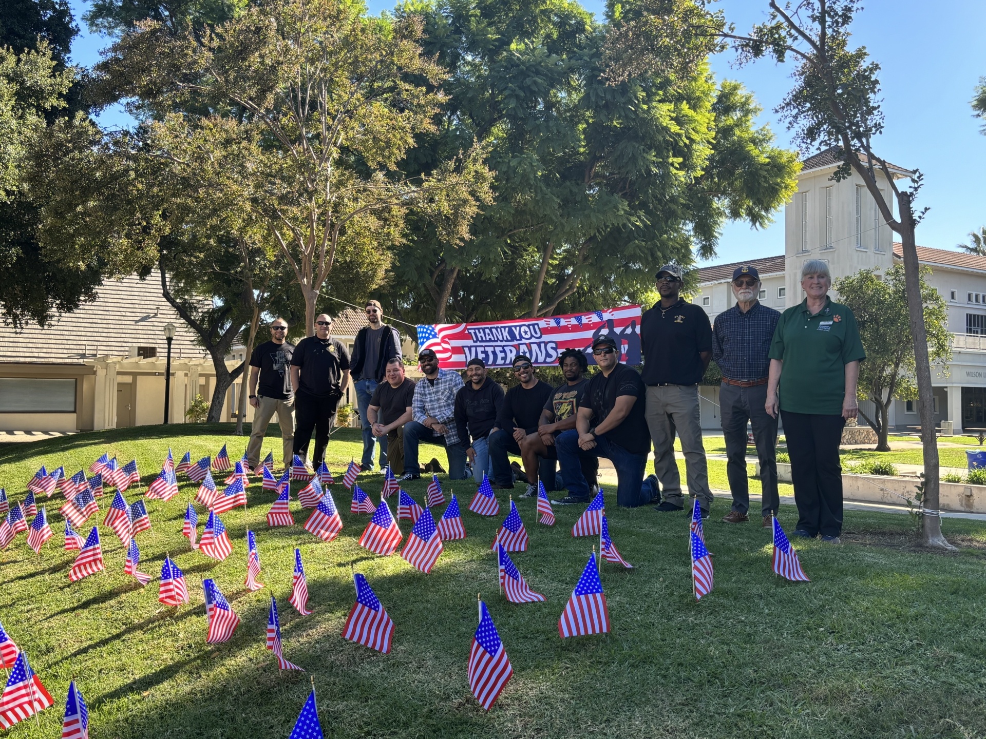 Veterans Day 2023 group photo in sneaky park in front of flags