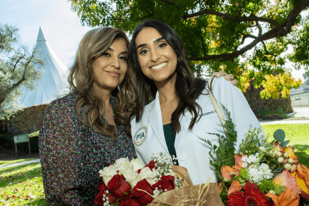 2023 White Coat Ceremony student smiling with parent outside with flowers